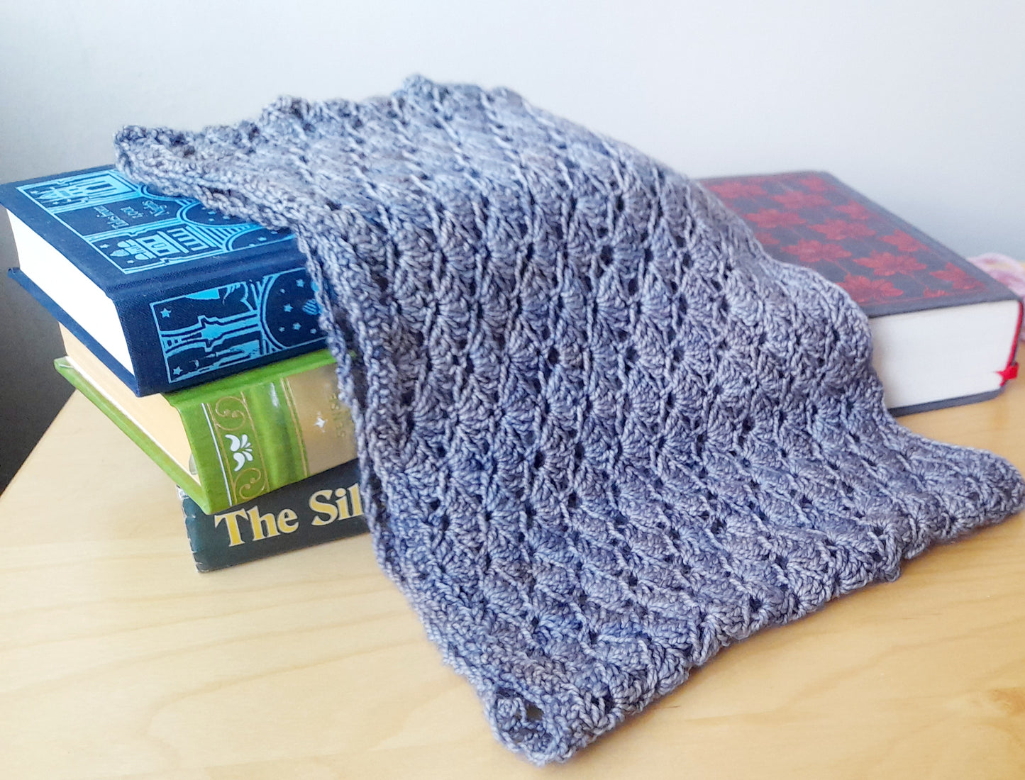 The wave cowl finished piece draped across some books. 